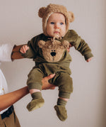A baby wearing the Wooly Organic embroidered sweater in tea leaf /savannah available at Babipur showing the popper fastener detail