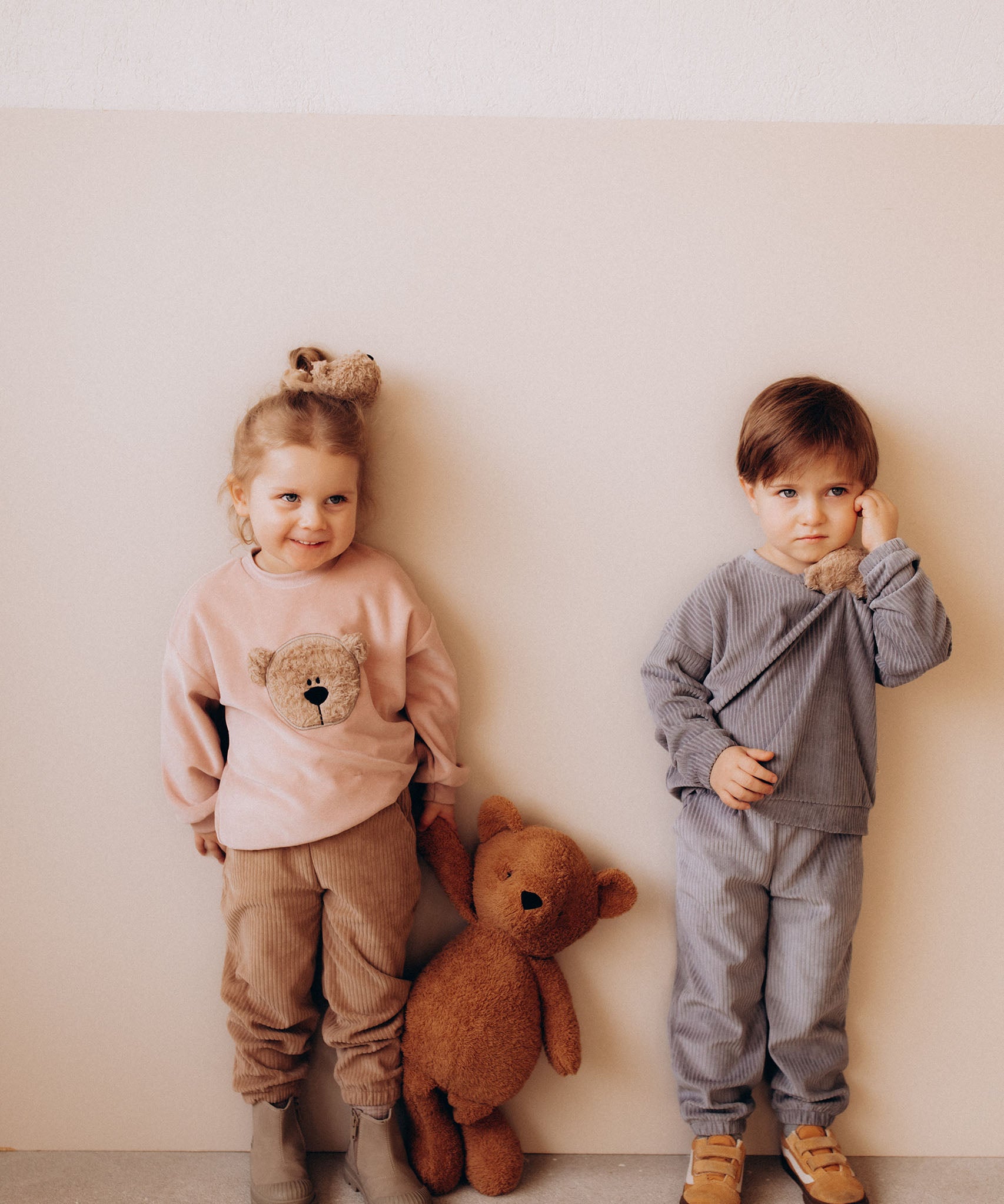 A child holding the Wooly Organic soft teddy bear by the hand and wearing the velour hair scrunchy, both available at Babipur.