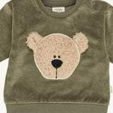 A close up of the Wooly Organic embroidered sweater in tea leaf green /savannah available at Babipur showing the cute fluffy teddy bear embroidery on the front and popper fastener detail
