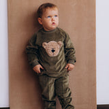 A child wearing the Wooly Organic embroidered GOTS organic cotton velour sweater in tea leaf /savannah available at Babipur. 