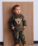 A child wearing the Wooly Organic embroidered GOTS organic cotton velour sweater in tea leaf /savannah available at Babipur. 