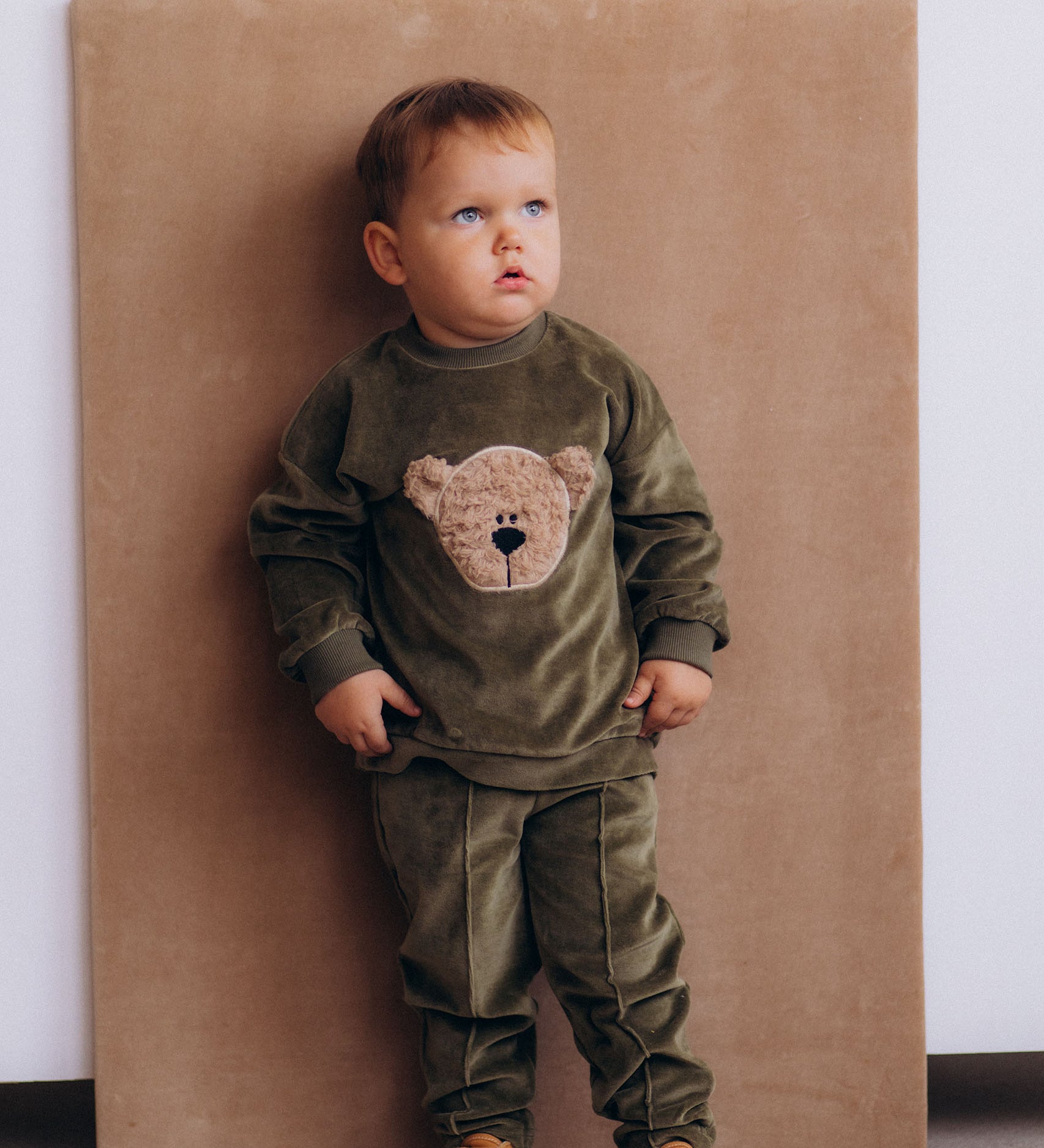 A child wearing the Wooly Organic embroidered GOTS organic cotton velour sweater in tea leaf /savannah available at Babipur. 
