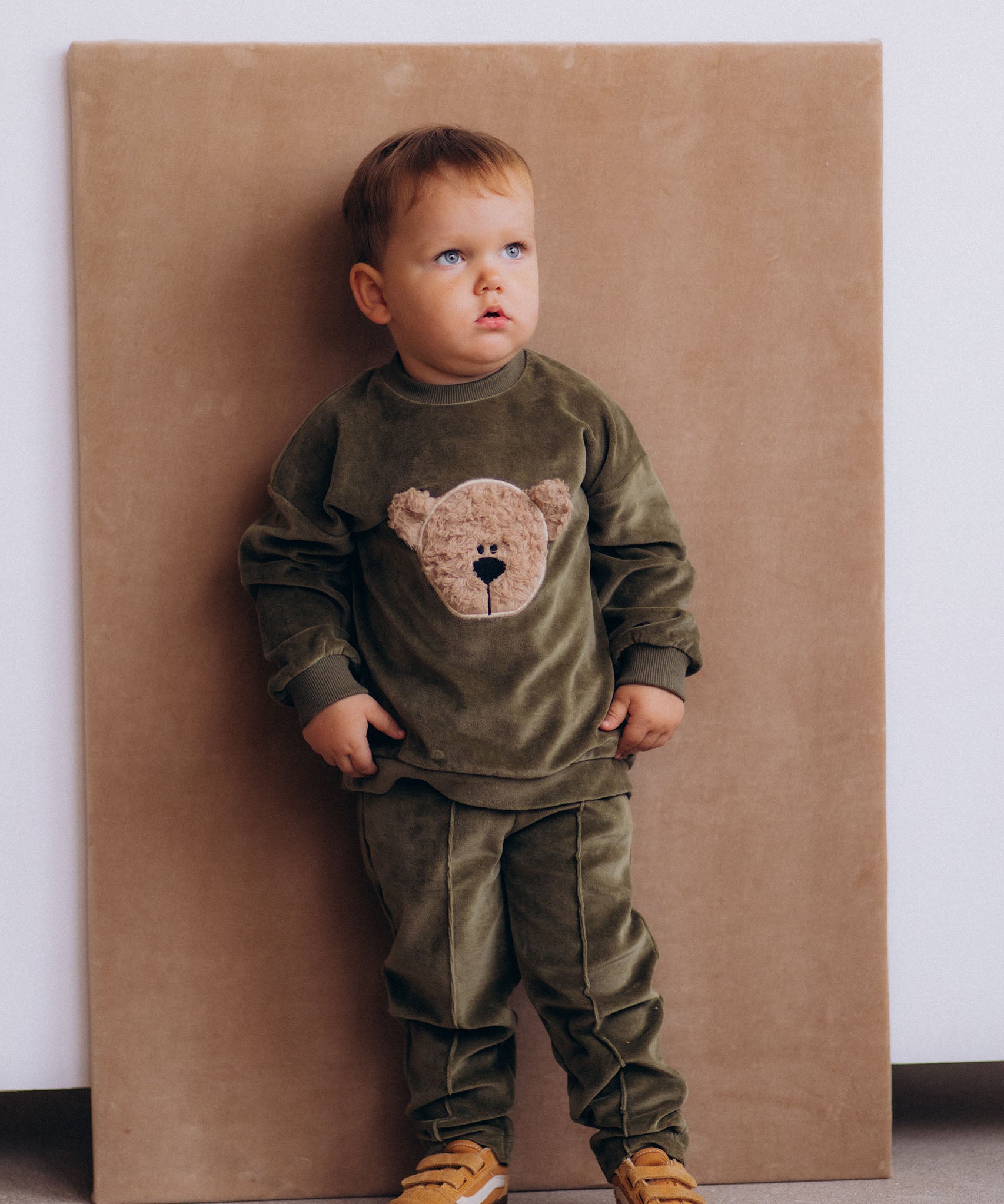 A child wearing the Wooly Organic embroidered GOTS organic cotton velour sweater in tea leaf /savannah available at Babipur. 