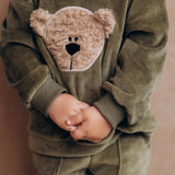 A close up of the velour detail and cute fluffy cream teddy embroidery on the A child wearing the Wooly Organic GOTS organic cotton velour sweater in tea leaf /savannah available at Babipur. 