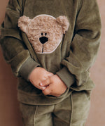 A close up of the velour detail and cute fluffy cream teddy embroidery on the A child wearing the Wooly Organic GOTS organic cotton velour sweater in tea leaf /savannah available at Babipur. 
