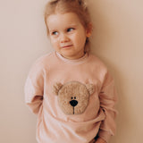 A child wearing the Wooly Organic GOTS organic cotton embroidered velour sweater in pale blush pink /savannah available at Babipur