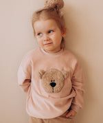 A child wearing the Wooly Organic GOTS organic cotton embroidered velour sweater in pale blush pink /savannah available at Babipur