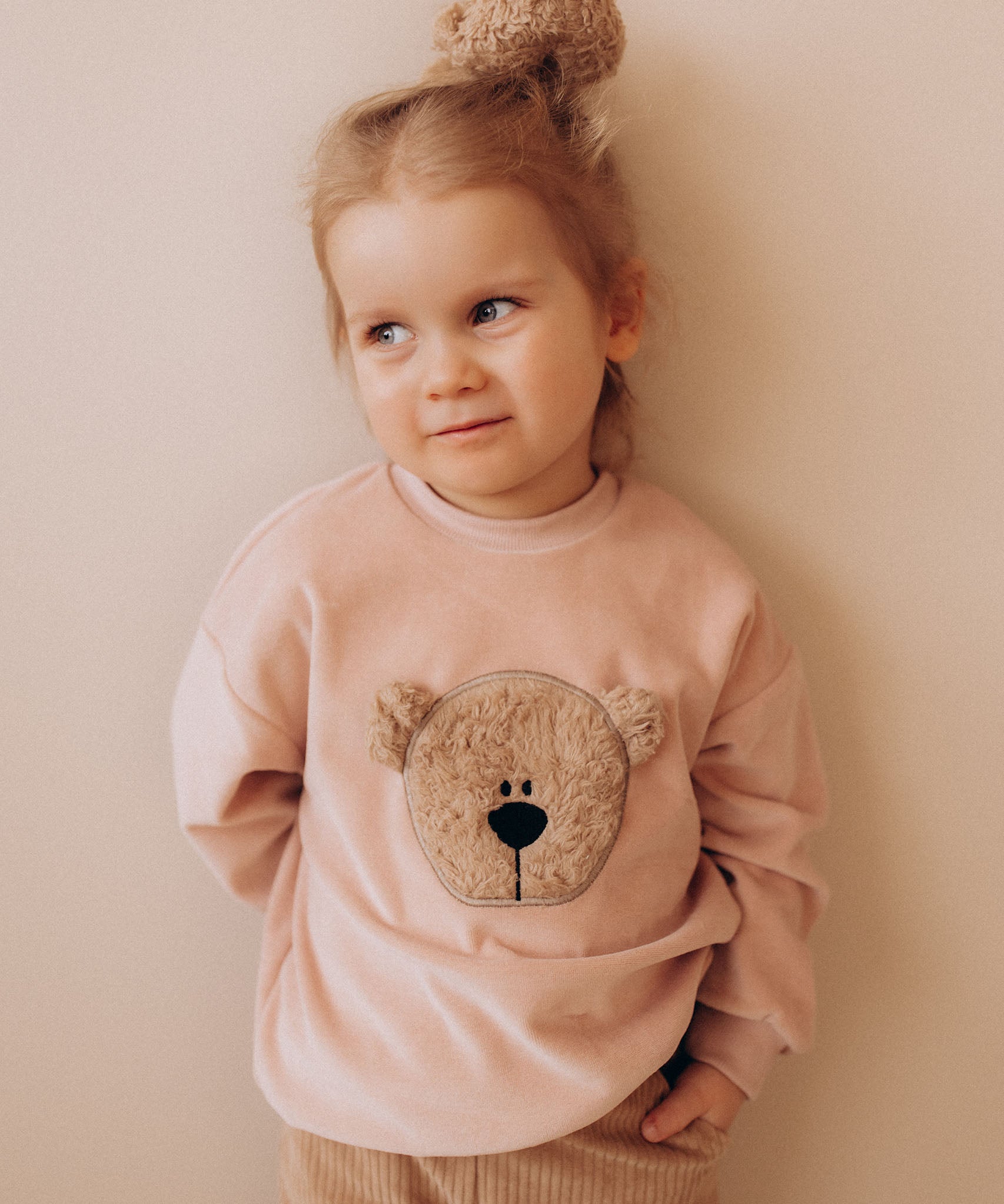 A child wearing the Wooly Organic GOTS organic cotton embroidered velour sweater in pale blush pink /savannah available at Babipur