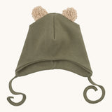 Wooly Organic hat with teddy ears in tea leaf / savannah available at Babipur. A light green GOTS organic hat in a soft ribbed style. Features ties and cute fluffy brown teddy bear ears