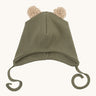 Wooly Organic hat with teddy ears in tea leaf / savannah available at Babipur. A light green GOTS organic hat in a soft ribbed style. Features ties and cute fluffy brown teddy bear ears