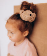 A close up of the cute fluffy teddy bear attached to the Wooly Organic scrunchy worn by a child and available at Babipur.