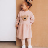 A child wearing the Wooly Organic velour scrunchy with a fluffy teddy on their head. Scrunchy available at Babipur. 