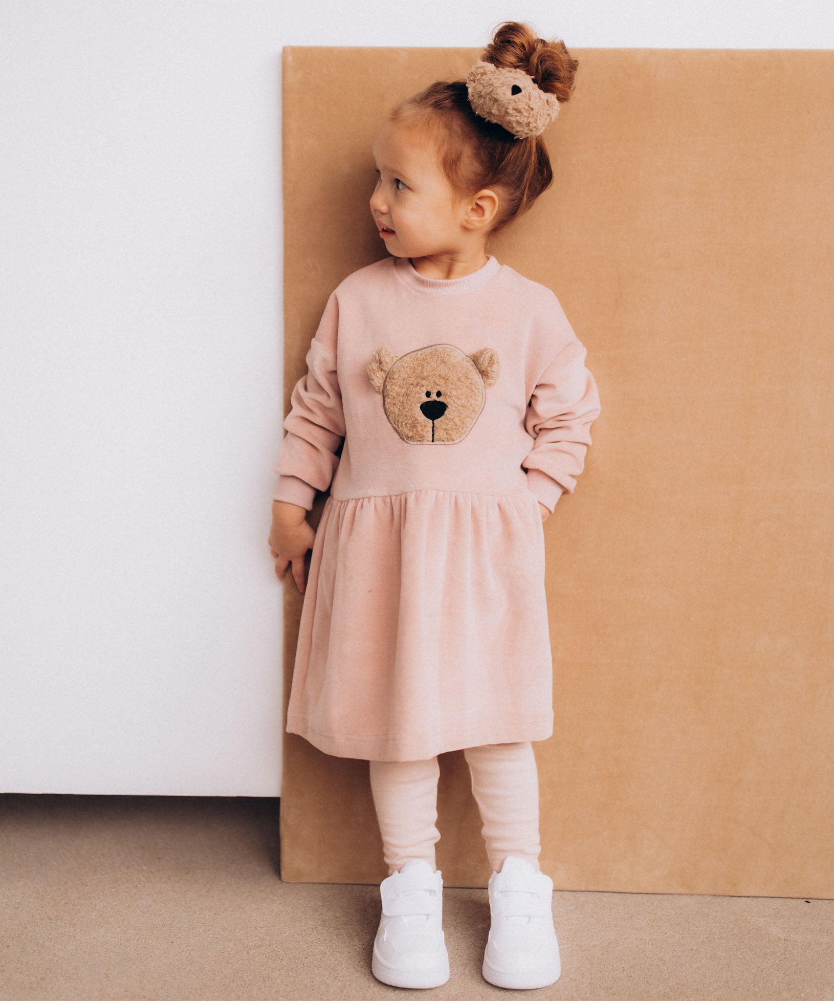 A child wearing the Wooly Organic velour scrunchy with a fluffy teddy on their head. Scrunchy available at Babipur. 