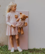A older child holding the Wooly Organic soft teddy bear in caramel brown with a pink tutu available at Babipur. 