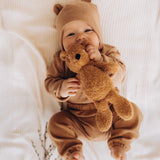 A baby holding and playing with the A small Wooly Organic soft teddy bear in brown available at Babipur. 