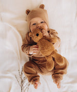 A baby holding and playing with the A small Wooly Organic soft teddy bear in brown available at Babipur. 