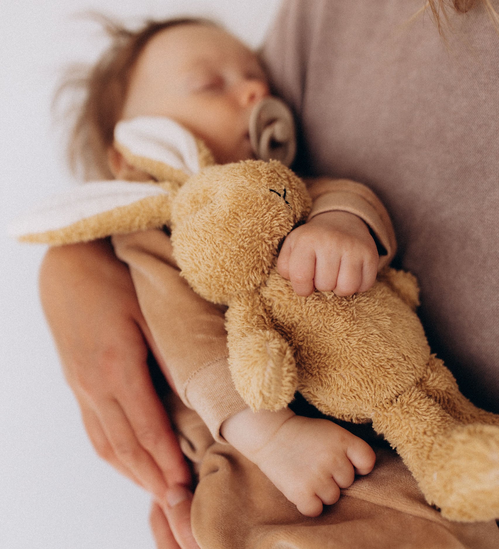 Baby holding a teddy bear with a blurred background