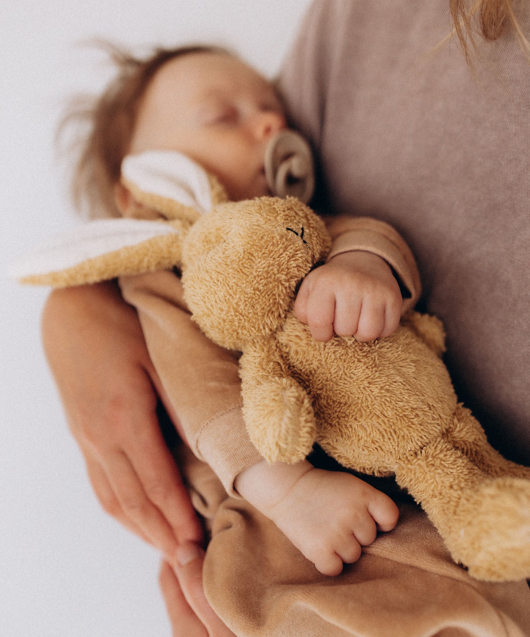 Baby holding a teddy bear with a blurred background