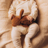 A close up of a baby holding onto the A small Wooly Organic soft teddy bear in brown available at Babipur. 