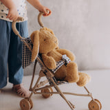 A toddler pushing the Wooly Organic soft cotton bunny rabbit toy in a toy pram. Bunny rabbit available at Babipur. 