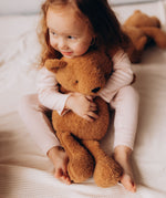 A small child hugging the Wooly Organic soft teddy bear in caramel brown available at Babipur.