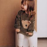 A girl wearing the Wooly Organic embroidered GOTS organic cotton velour sweater in tea leaf /savannah available at Babipur. 