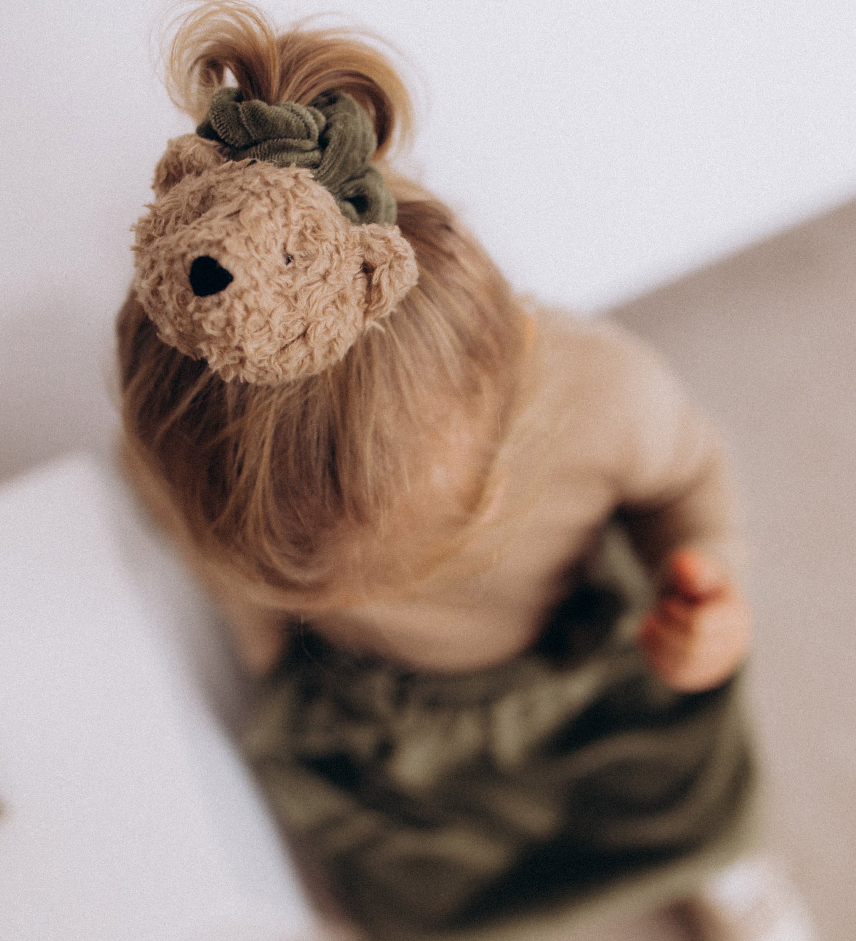 A child wearing the Wooly Organic velour scrunchy in tea leaf green available at Babipur. 