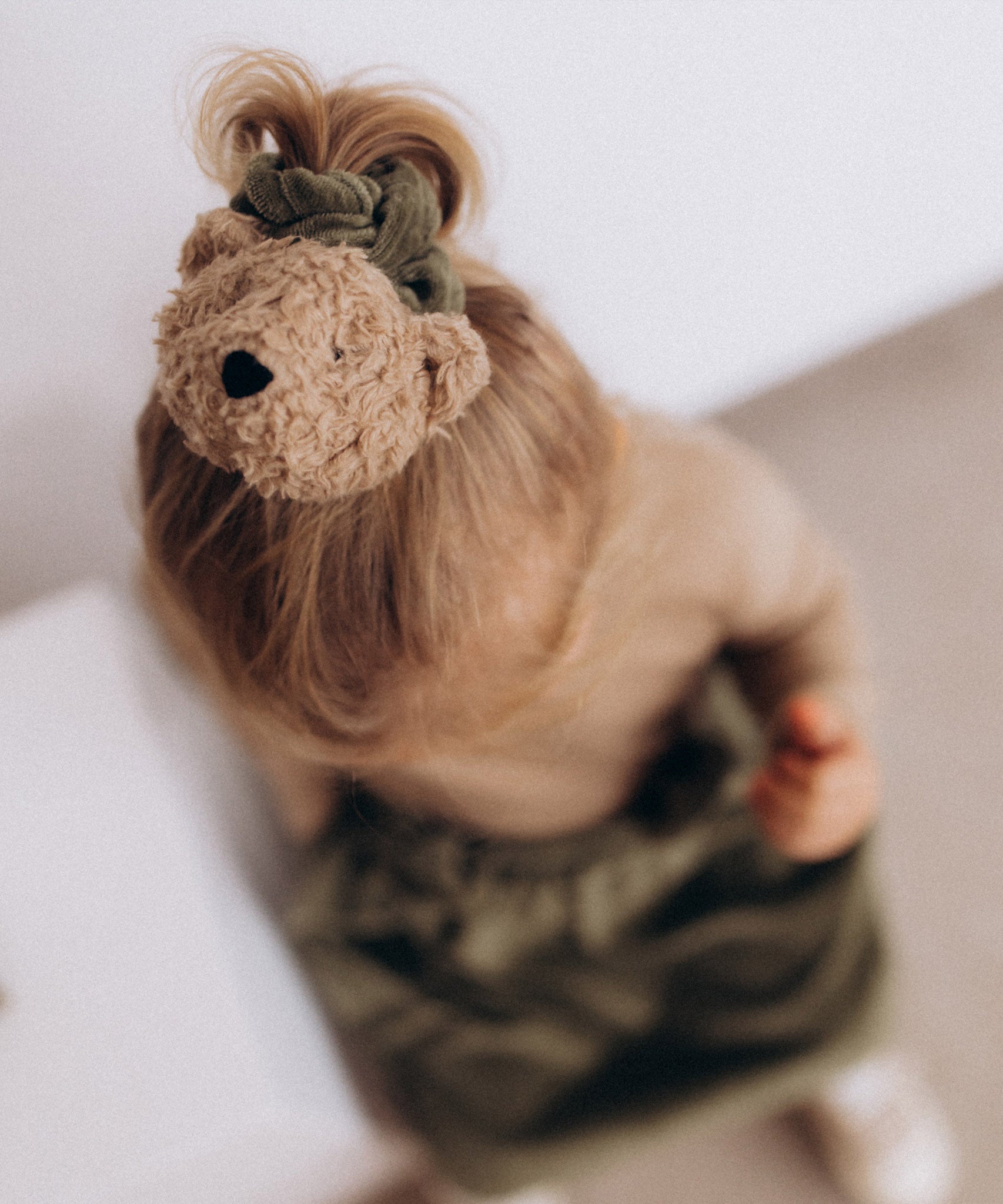 A child wearing the Wooly Organic velour scrunchy in tea leaf green available at Babipur. 