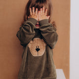 A child playing and wearing the Wooly Organic embroidered GOTS organic cotton velour sweater in tea leaf /savannah available at Babipur. 