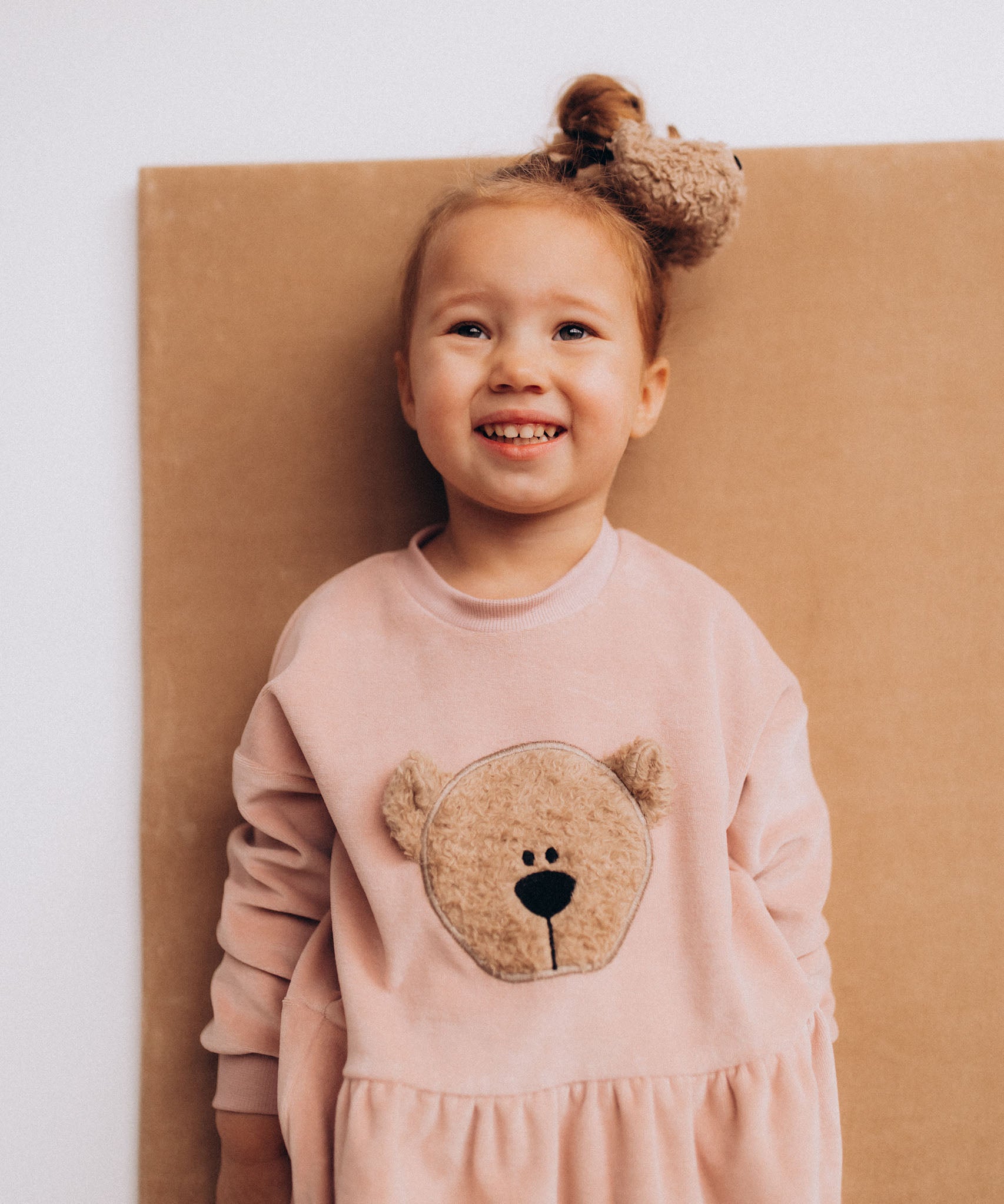 A close up of a child wearing the Wooly Organic embroidered velour dress in pale blush pink /savannah available at Babipur showing the fluffy teddy bear embroidery detail