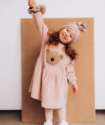 A child modelling the Wooly Organic embroidered velour dress in pale blush pink /savannah available at Babipur showing the fluffy teddy bear embroidery detail on GOTS organic cotton fabric