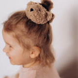 A close up of a child wearing the Wooly Organic velour scrunchy available at Babipur showing the cute fluffy teddy bear detail