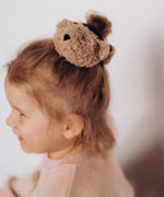 A close up of a child wearing the Wooly Organic velour scrunchy available at Babipur showing the cute fluffy teddy bear detail