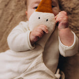 A close up of a baby holding a Wooly Organic goose heating pad, showing it's cute facial features. This heating pad is available at Babipur. 