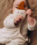 A close up of a baby holding a Wooly Organic goose heating pad, showing it's cute facial features. This heating pad is available at Babipur. 