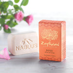 Zaytoun Pure Olive Oil Soap - Rose 100g. A beautiful rose scented Nablus soap bar, stood next to the box with a rose plant in the background