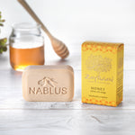 Zaytoun Pure Olive Oil Soap - Honey 100g, next to its box and stood in front of a glass jar of honey