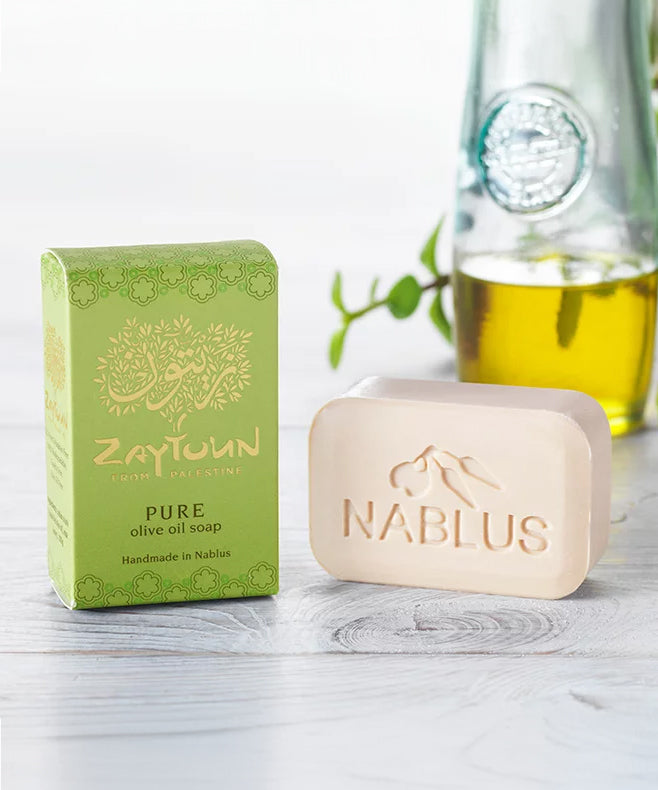 Zaytoun Pure Olive Oil Soap 100g, next to its box and stood in front of a glass jar of olive oil
