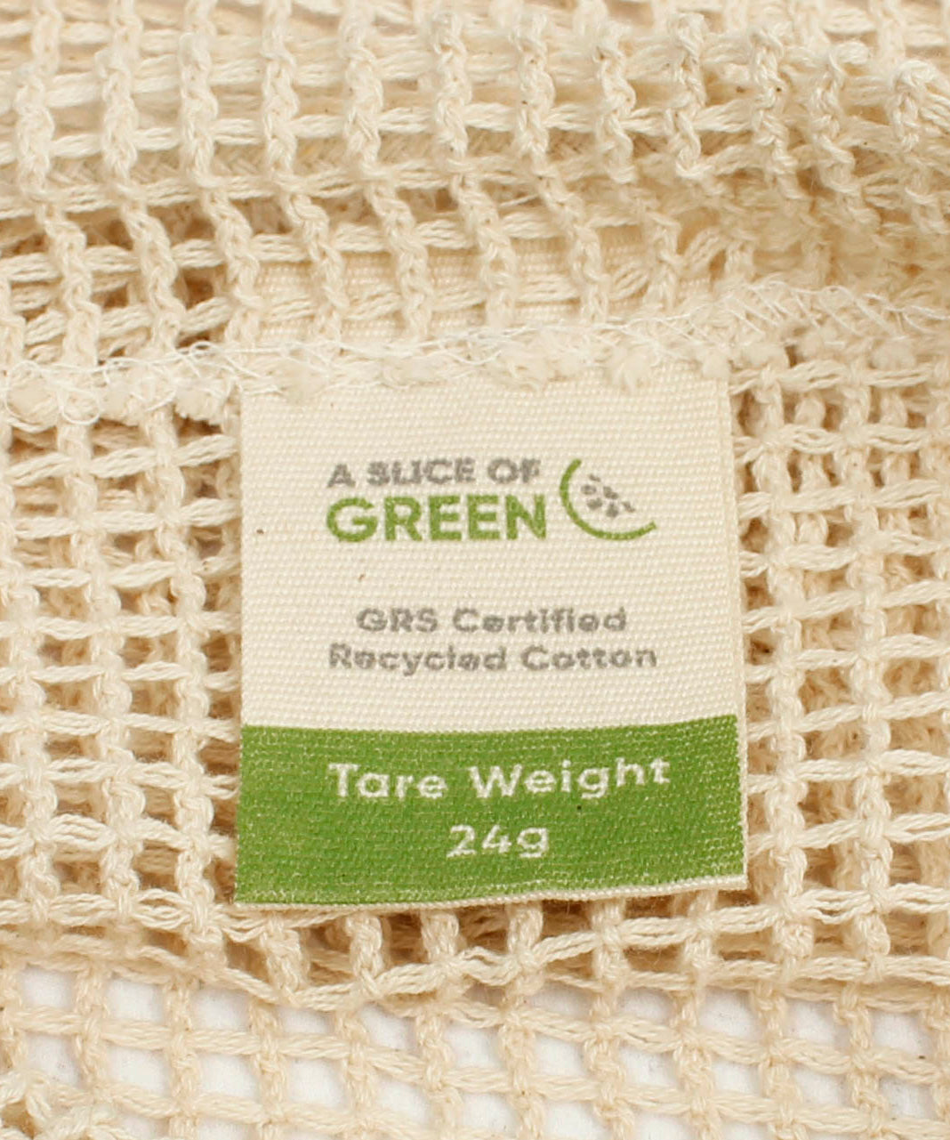 A close up view of the A Slice Of Green small mesh recycled cotton produce bag showing the mesh detail. Features a tag showing the total carry weight and recycled cotton certification 