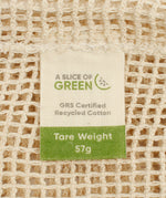 A close up view of the A Slice Of Green large mesh recycled cotton produce bag showing the mesh detail. Features a tag showing the total carry weight and recycled cotton certification 