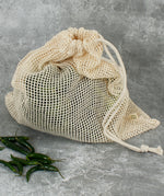 A closed A Slice Of Green large mesh produce bag made showing fresh produce inside and the drawstring detail