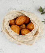 A close up of the A Slice Of Green large mesh produce bag showing the mesh detail with a bunch of potatoes inside showing scale