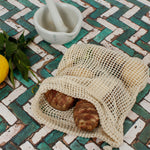 A Slice Of Green small mesh produce bag made from recycled cotton showing a opened bag with a bunch of food items inside. 