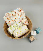 A close up of the A Slice Of Green rainbow muslin cloth set in a Respiin bowl next to 3 wooden coloured blocks 