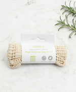 A Slice Of Green small mesh recycled cotton produce bag laid flat on a stone surface. 