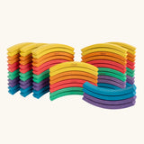 Set of 72 Abel curved wooden blocks in rainbow colors, including yellow, orange, red, purple, blue and green placed in stacks. 12 blocks in each colour. 