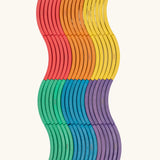Set of 72 Abel curved wooden blocks in rainbow colors, including yellow, orange, red, purple, blue and green placed in a wavy pattern. 12 blocks in each colour. 