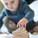 Close up of a boy stacking the Abel Waldorf wooden Golden Ratio blocks on a white sheet