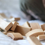 Close up of a pile of Abel Golden Ratio stacking wooden toy blocks on a white bed