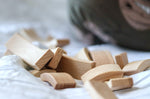 Close up of a pile of Abel Golden Ratio stacking wooden toy blocks on a white bed